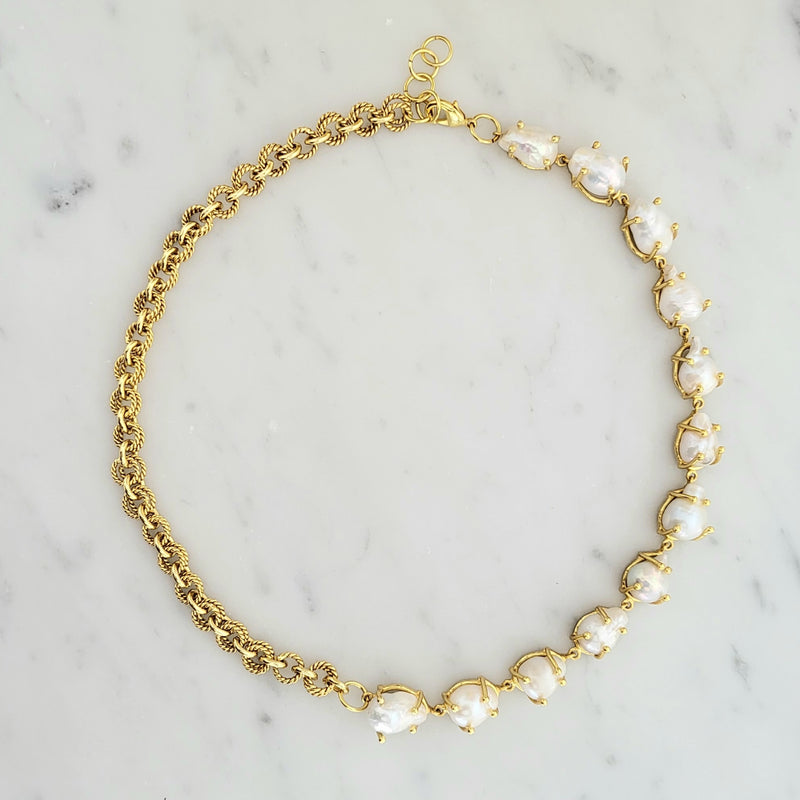 Gold necklace with pearl-like beads on a marble background