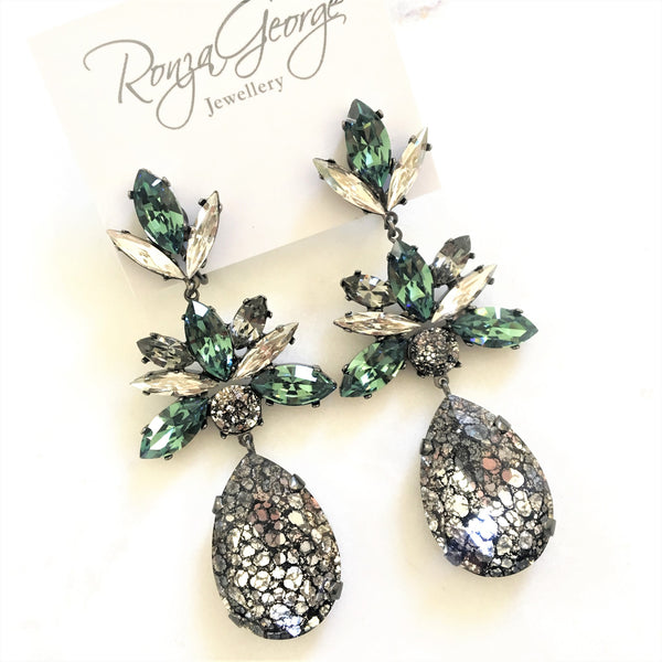 A pair of statement earrings with green, and black color scheme, featuring a pear-shaped setting in a black plated setting, brand name 'Ronza George'.